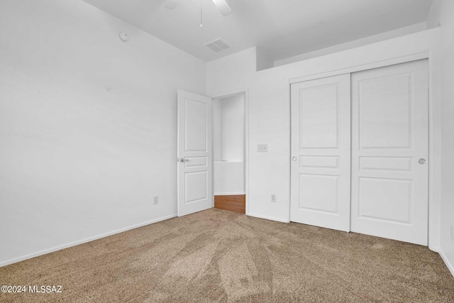 unfurnished bedroom featuring carpet floors, a closet, and ceiling fan