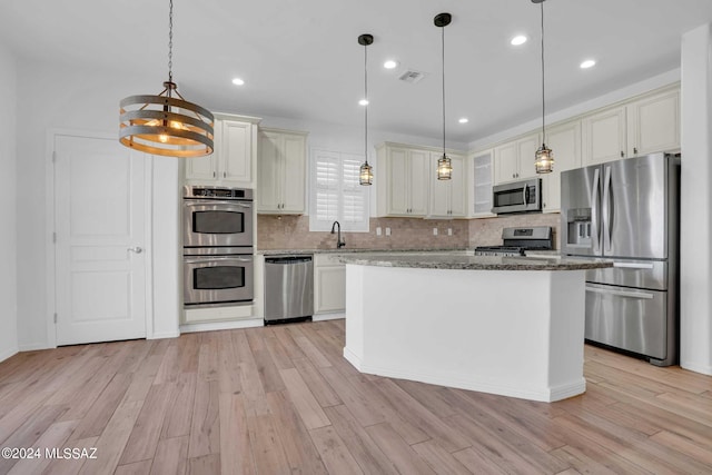 kitchen featuring a center island, light wood-type flooring, stainless steel appliances, and hanging light fixtures