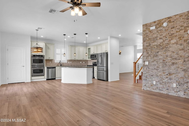 kitchen with stainless steel appliances, decorative light fixtures, light hardwood / wood-style flooring, white cabinets, and a kitchen island