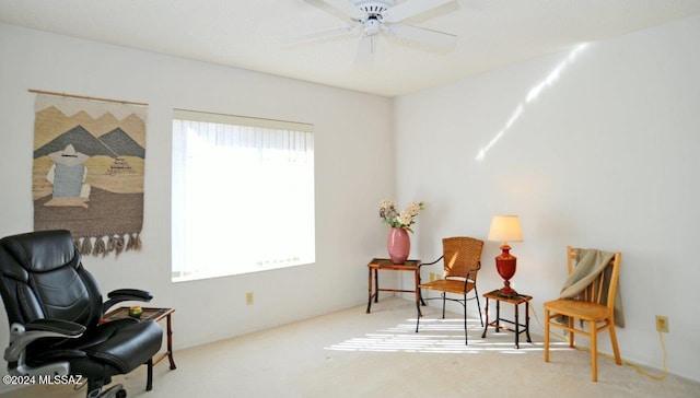 living area featuring light colored carpet and ceiling fan