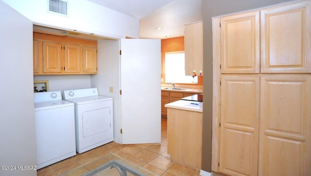 washroom featuring separate washer and dryer, sink, light tile patterned floors, and cabinets