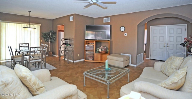 living room with ceiling fan, dark parquet flooring, and a textured ceiling