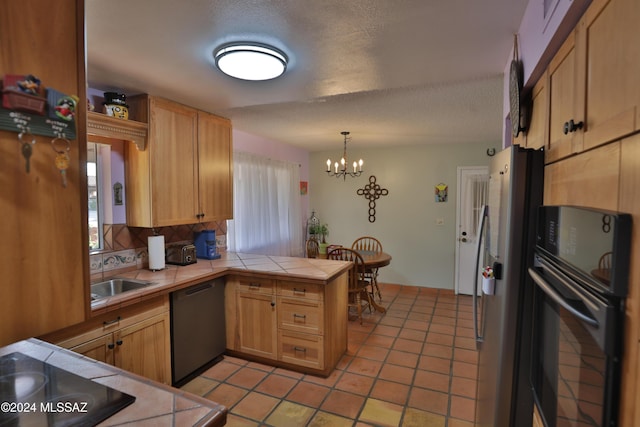 kitchen featuring kitchen peninsula, a textured ceiling, sink, black appliances, and tile countertops