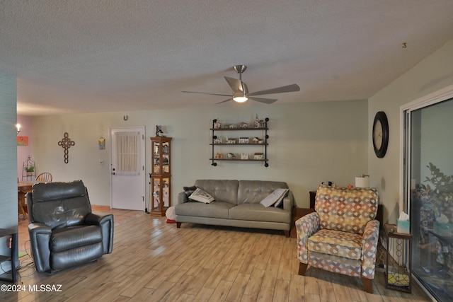 living room with ceiling fan, light hardwood / wood-style floors, and a textured ceiling