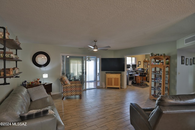 living room with ceiling fan and a textured ceiling