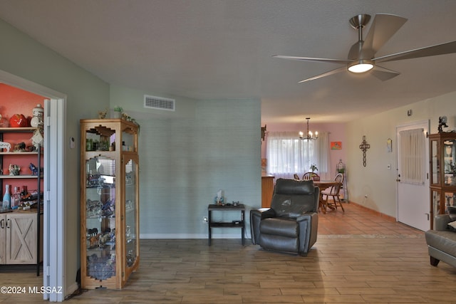 living room with wood-type flooring and ceiling fan with notable chandelier