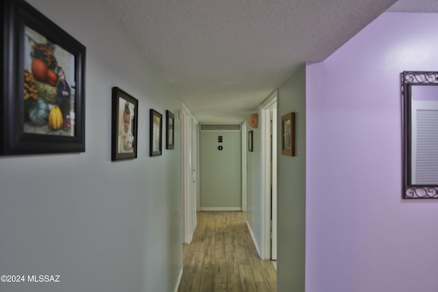 corridor with a textured ceiling and light wood-type flooring