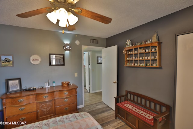 bedroom featuring hardwood / wood-style floors, a textured ceiling, and ceiling fan