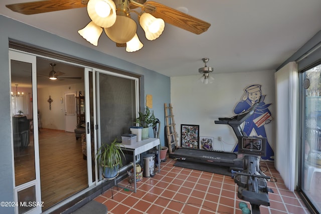 workout area featuring tile patterned floors and ceiling fan with notable chandelier