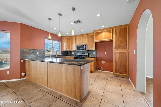 kitchen with decorative light fixtures, light tile patterned flooring, kitchen peninsula, and appliances with stainless steel finishes