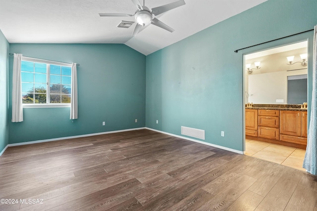 unfurnished bedroom featuring vaulted ceiling, ceiling fan, ensuite bath, and light hardwood / wood-style floors