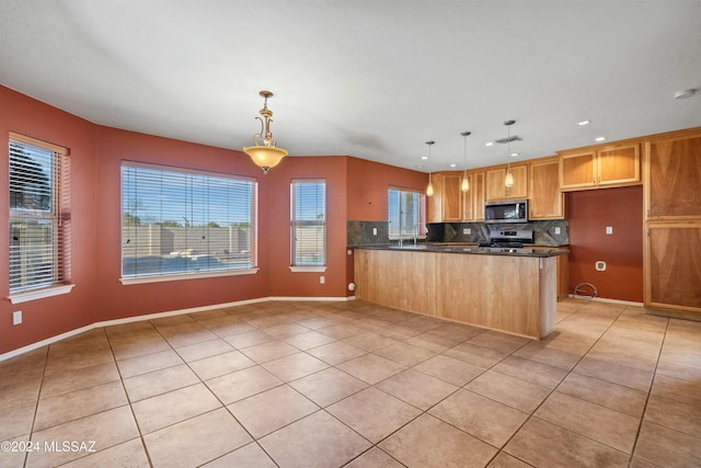 kitchen featuring light tile patterned flooring, appliances with stainless steel finishes, decorative light fixtures, and kitchen peninsula