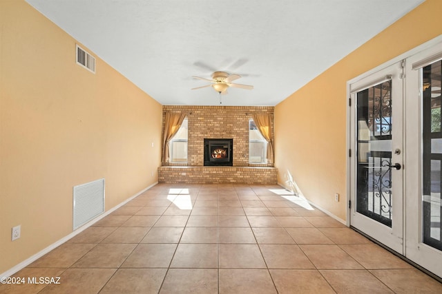 unfurnished living room with light tile patterned flooring, brick wall, a wealth of natural light, and a fireplace