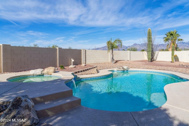 view of pool featuring a mountain view, pool water feature, and an in ground hot tub