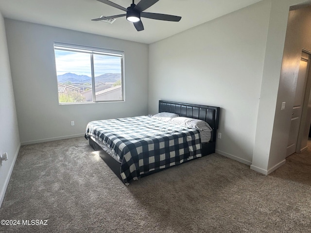 bedroom with a mountain view, dark carpet, and ceiling fan