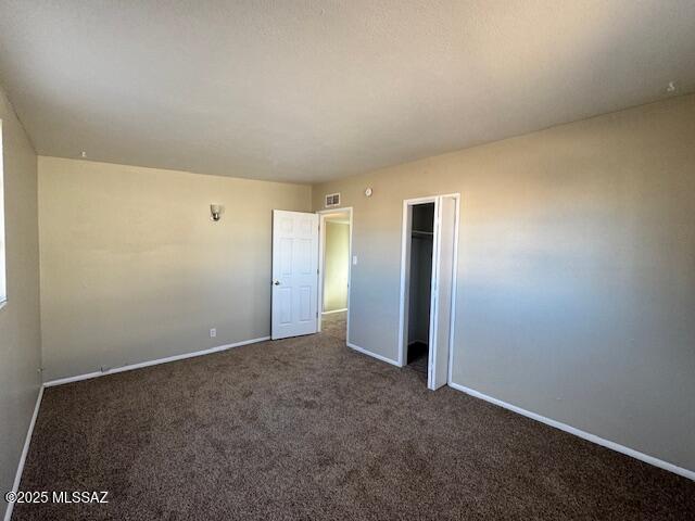 unfurnished bedroom with a closet and dark colored carpet