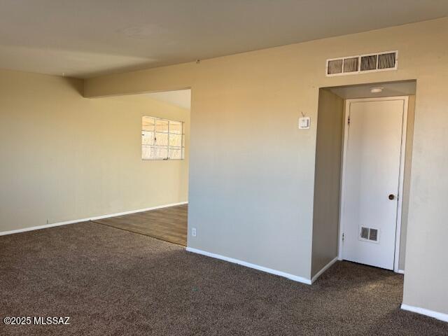 unfurnished room featuring dark carpet