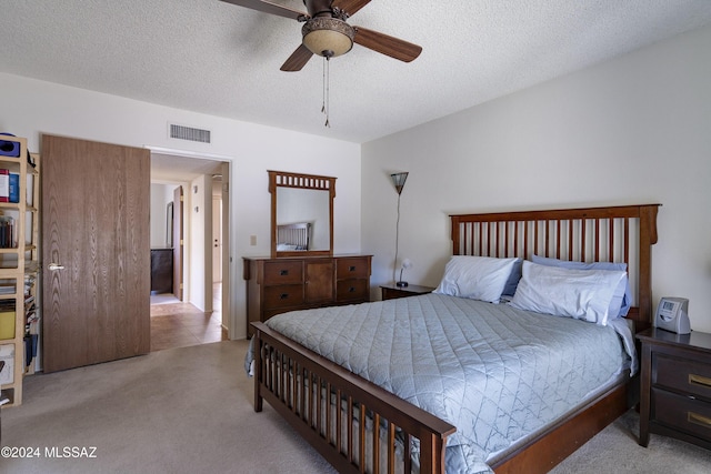 carpeted bedroom featuring a textured ceiling and ceiling fan