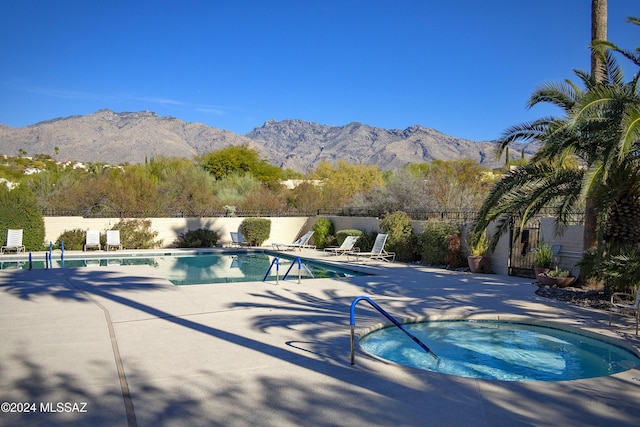 view of pool featuring a mountain view, a patio, and a hot tub