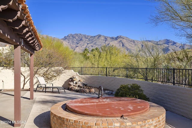 view of patio / terrace featuring a covered hot tub, a fenced backyard, and a mountain view