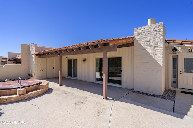 rear view of property with a tile roof and a patio