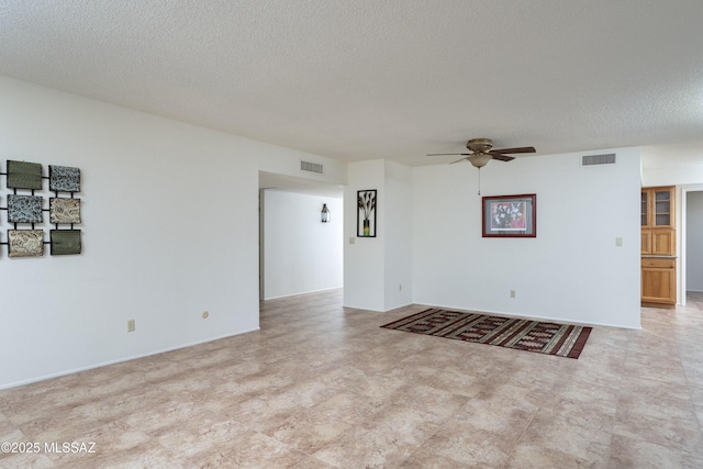 empty room featuring ceiling fan, a textured ceiling, and visible vents