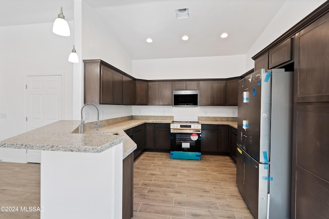 kitchen with sink, stainless steel appliances, kitchen peninsula, pendant lighting, and light wood-type flooring