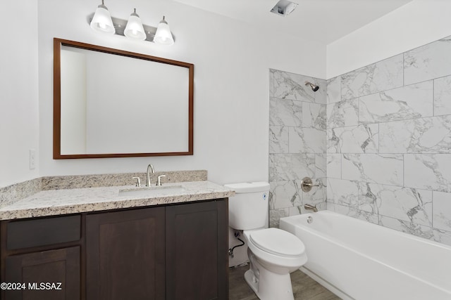 full bathroom featuring vanity, tiled shower / bath combo, and toilet