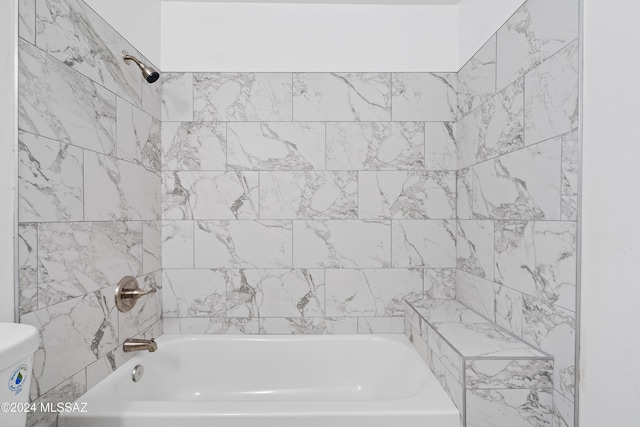 bathroom with tiled shower / bath combo and toilet