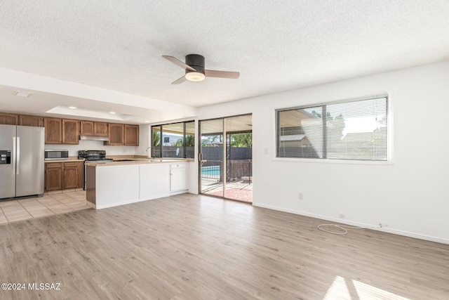 kitchen with kitchen peninsula, stainless steel appliances, ceiling fan, and light hardwood / wood-style floors