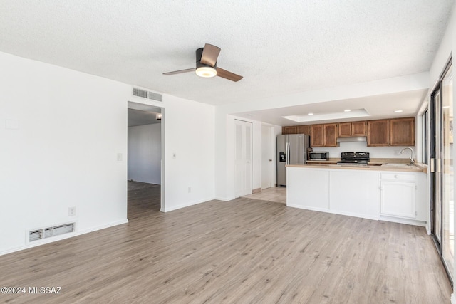 kitchen with kitchen peninsula, light wood-type flooring, stainless steel appliances, ceiling fan, and sink