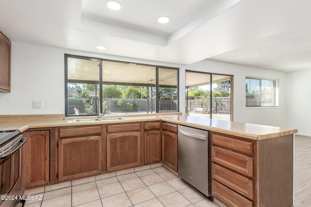 kitchen with sink, stainless steel appliances, a raised ceiling, kitchen peninsula, and light tile patterned flooring