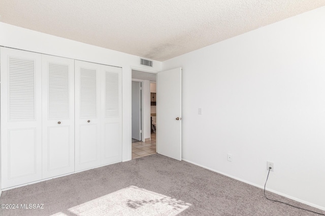 unfurnished bedroom featuring a closet, light colored carpet, and a textured ceiling