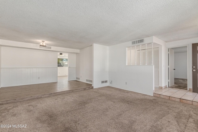 unfurnished living room featuring light colored carpet and a textured ceiling