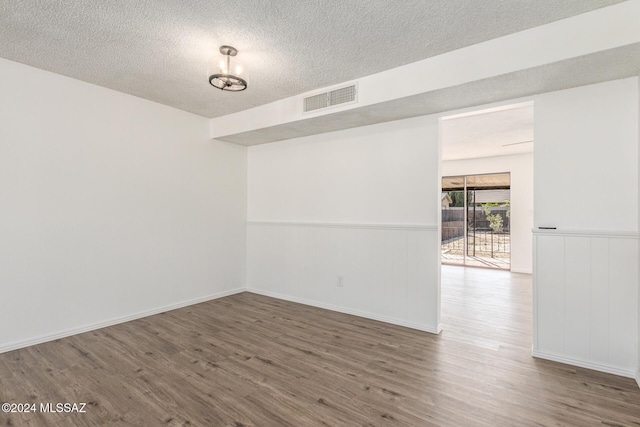 spare room featuring hardwood / wood-style floors and a textured ceiling