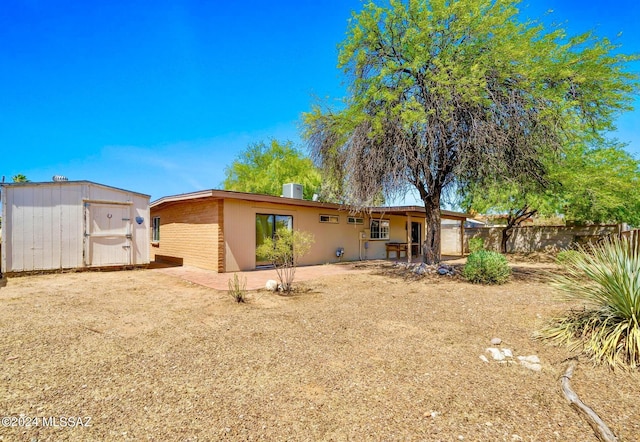 rear view of property featuring central AC unit and a shed