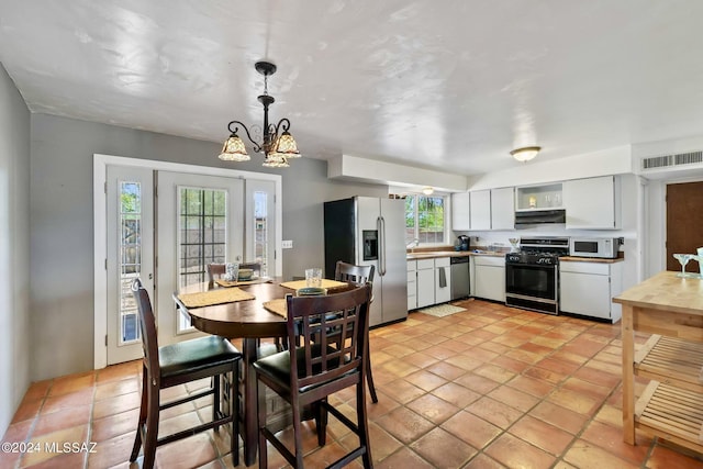 kitchen with white cabinetry, an inviting chandelier, hanging light fixtures, light tile patterned floors, and appliances with stainless steel finishes