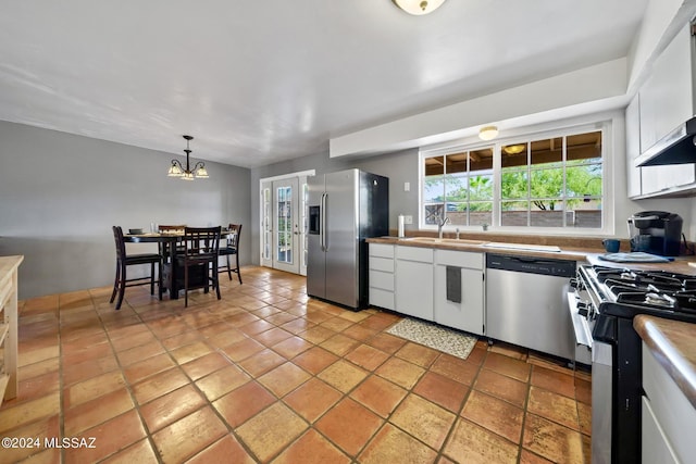 kitchen with french doors, sink, white cabinetry, hanging light fixtures, and stainless steel appliances