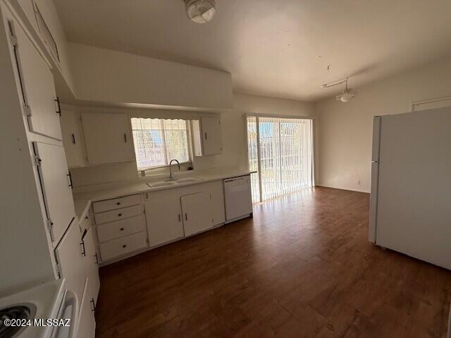 kitchen featuring a wealth of natural light, white cabinetry, sink, and white appliances