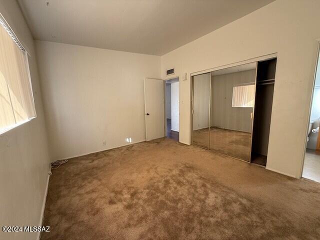 unfurnished bedroom with multiple windows, a closet, and carpet floors