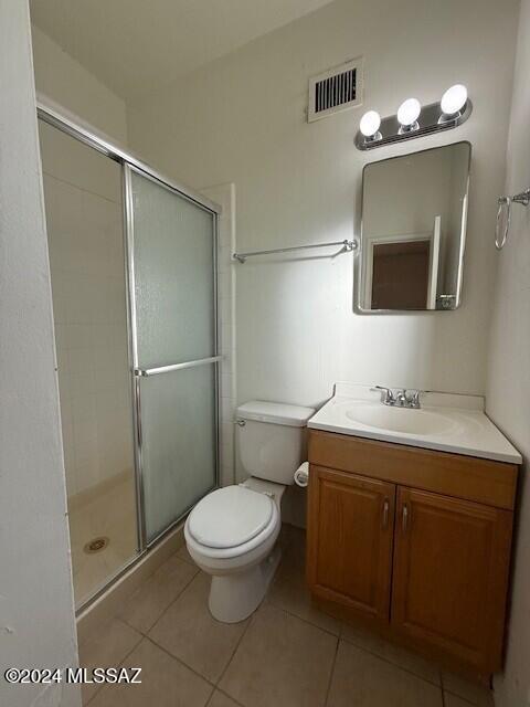 bathroom with tile patterned floors, toilet, vanity, and walk in shower