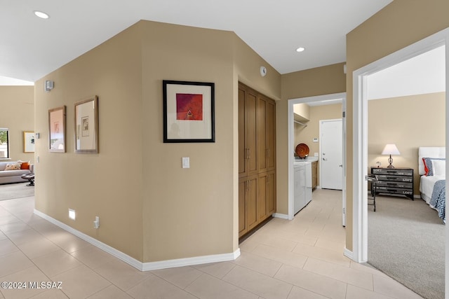 hall with light colored carpet and independent washer and dryer