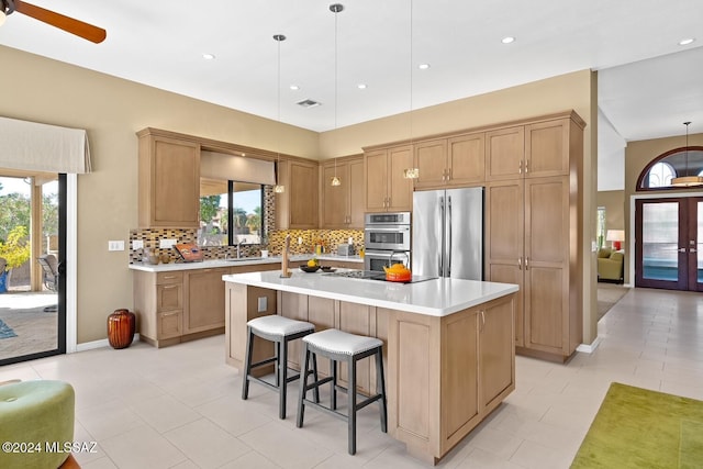 kitchen featuring stainless steel appliances, a healthy amount of sunlight, a kitchen island with sink, and pendant lighting