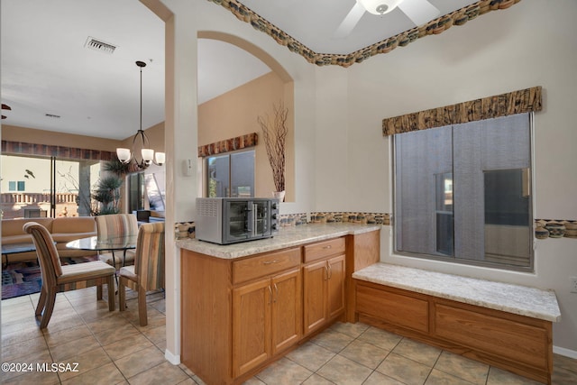 kitchen with light tile patterned floors, ceiling fan with notable chandelier, and hanging light fixtures