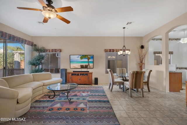 tiled living room with ceiling fan with notable chandelier