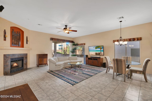 tiled living room featuring ceiling fan with notable chandelier and a tiled fireplace