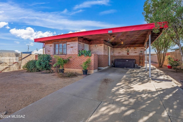 view of front of property with a carport and a hot tub