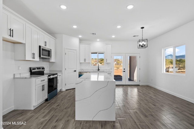 kitchen featuring pendant lighting, dark hardwood / wood-style floors, appliances with stainless steel finishes, a kitchen island, and white cabinetry