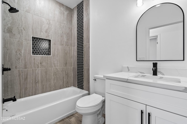 full bathroom with hardwood / wood-style floors, vanity, tiled shower / bath combo, and toilet