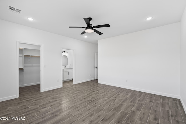 unfurnished bedroom featuring a closet, a spacious closet, ceiling fan, and dark wood-type flooring